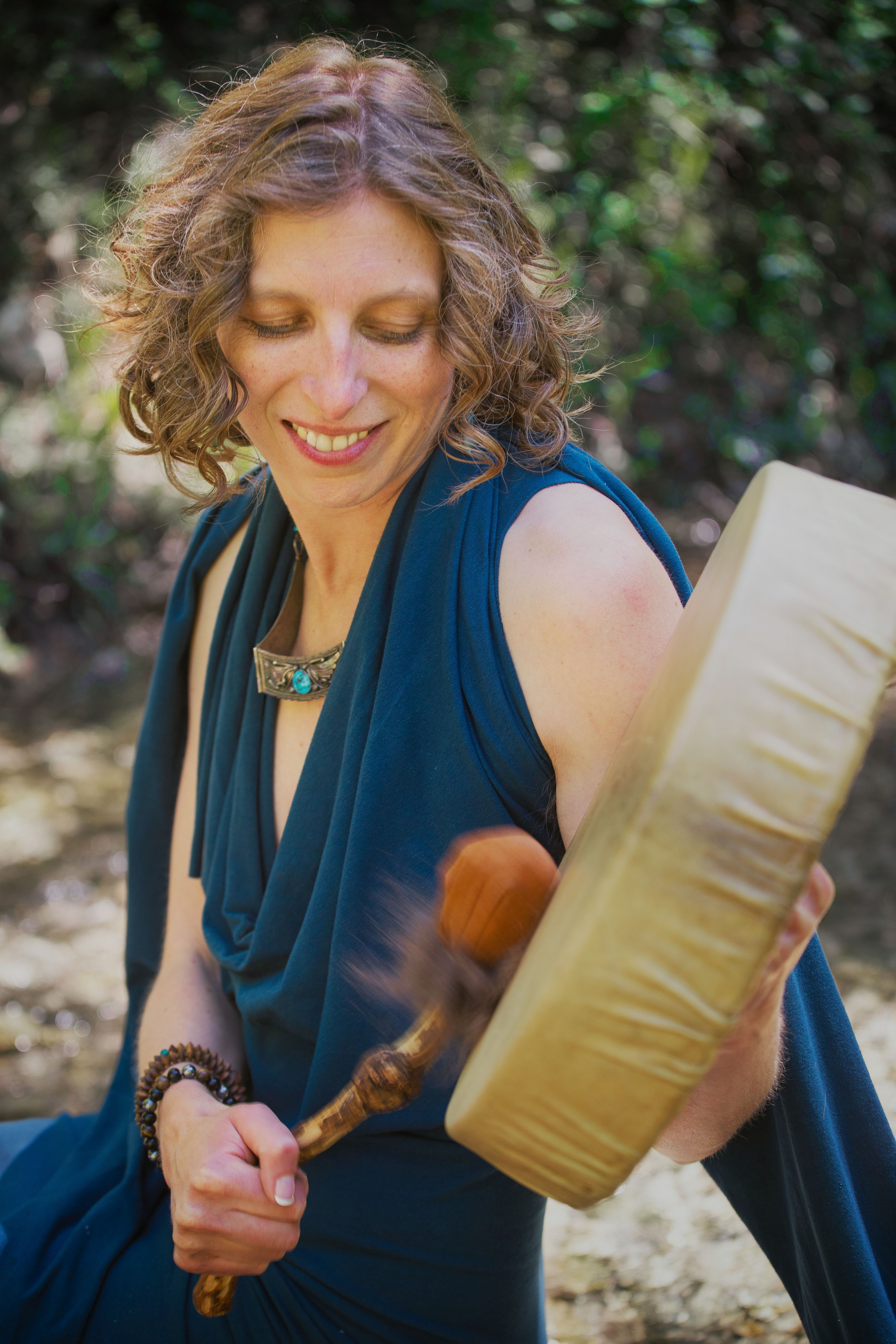 Spiritual woman beating a shamanic healing drum with an animal hide beater