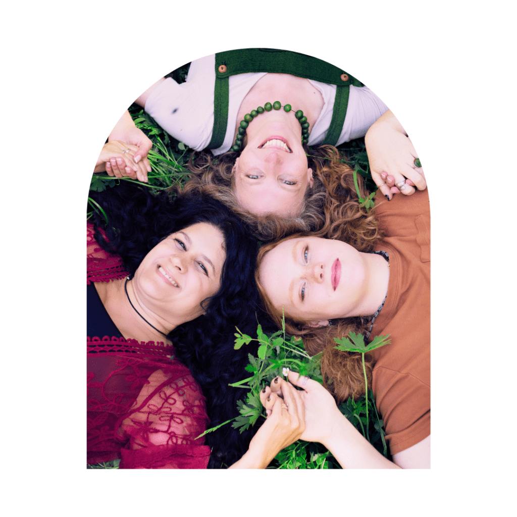 three spiritual woman laying on the grass holding hands