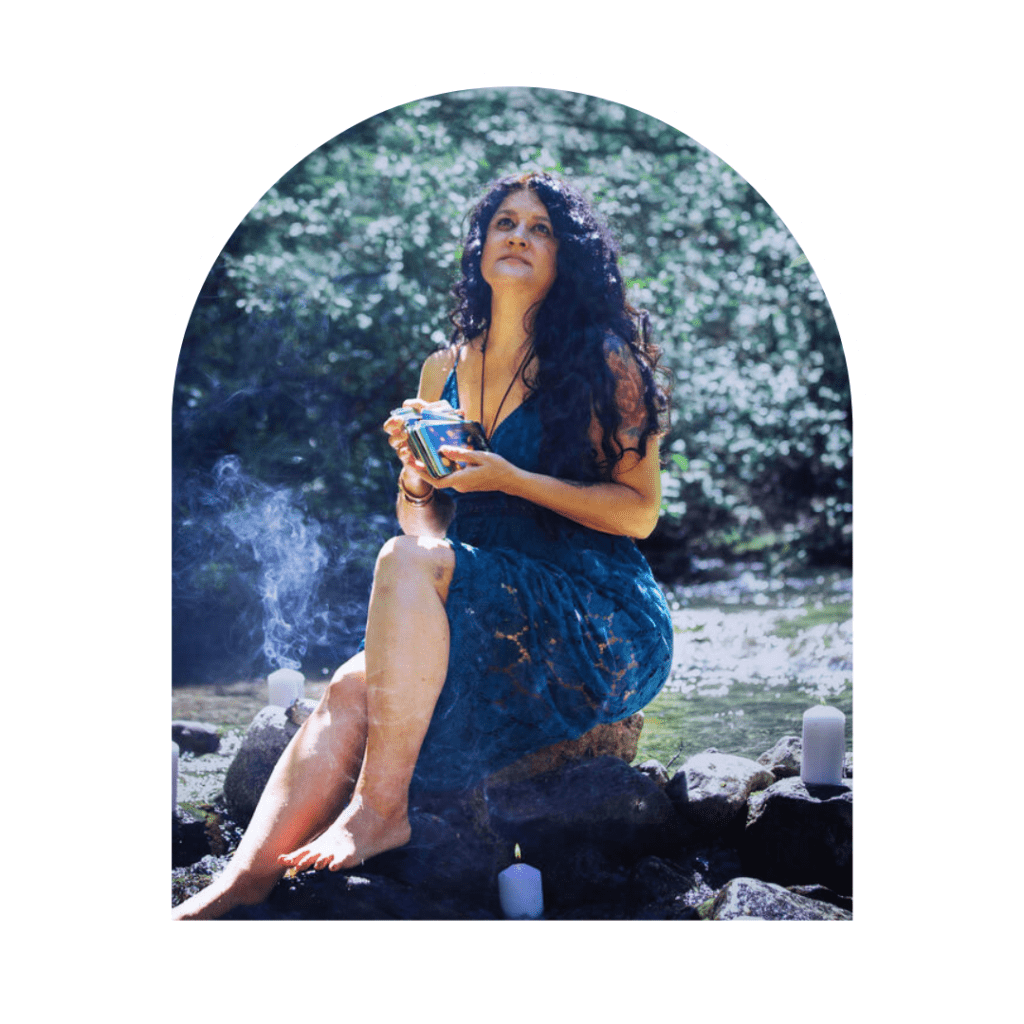 spiritual woman holding a tarot deck on top of a rock in a creek