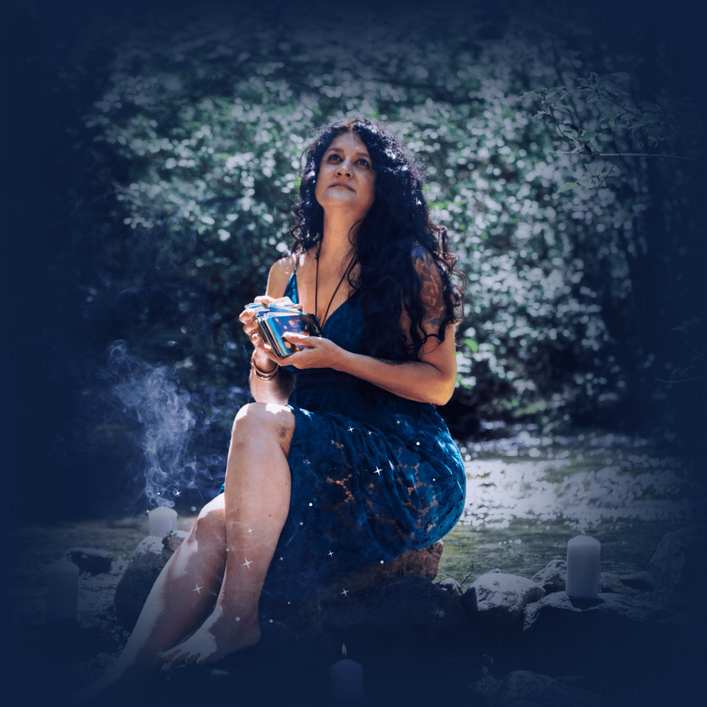 spiritual woman on a rock in a riverbed holding a deck of tarot cards