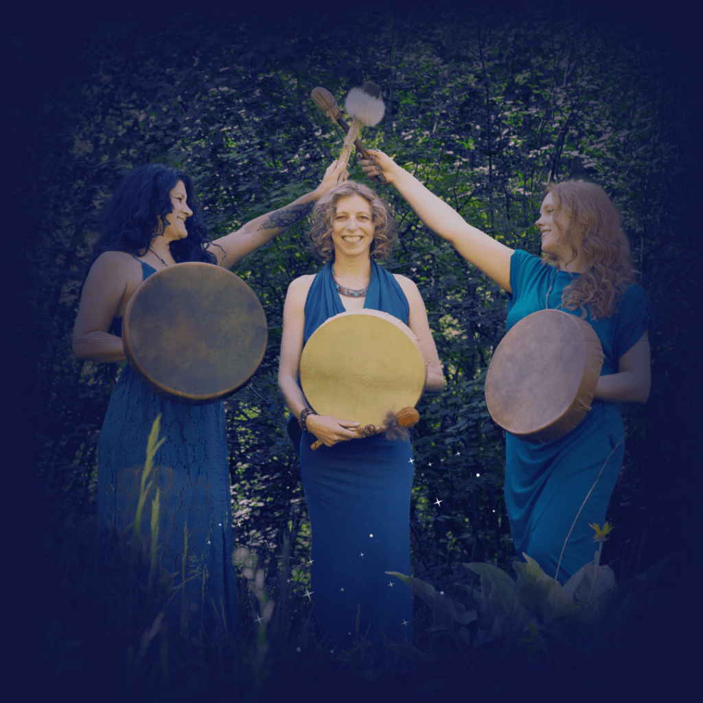 three spiritual women with shamanic drums and beaters creating a pyramid shape with their arms